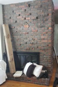 a living room with a brick fireplace and wood floors