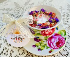 a teacup filled with flowers sitting on top of a plate next to a candle