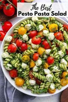 a white bowl filled with pasta salad next to tomatoes and broccoli on a wooden cutting board