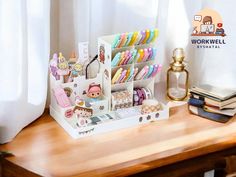 a wooden desk topped with lots of toys and books next to a white curtained window