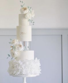 three tiered wedding cake with white flowers and greenery