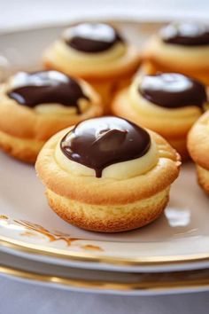 chocolate covered cookies on a plate with gold trimmings and white frosting, sitting next to each other