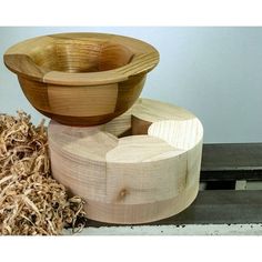 three wooden bowls sitting on top of each other next to some wood shavings