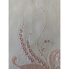 an embroidered piece with beads and pearls on it's side, in light pink