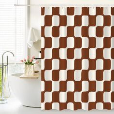 a bathroom with a brown and white shower curtain next to a bathtub in front of a window