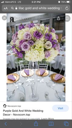 a vase filled with purple and white flowers sitting on top of a table next to plates