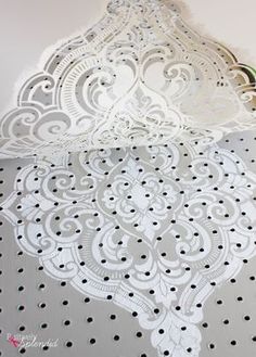 the white lace is being cut out on top of the doily to make it look like