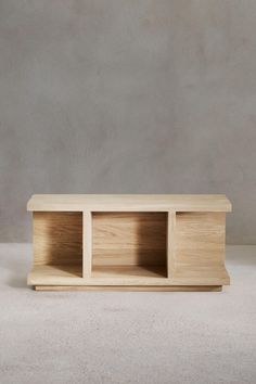 a wooden shelf sitting on top of a white floor next to a gray wall with two shelves in the middle