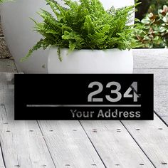 a house number sign sitting on top of a wooden table next to a potted plant