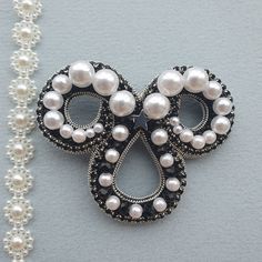 a close up of a brooch with pearls