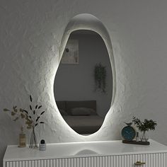 a white dresser topped with a mirror next to a couch and potted plant on top of it