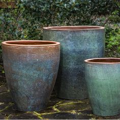 three large pots sitting on top of a stone ground