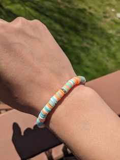 a person's arm with a bracelet that has an orange and blue bead on it