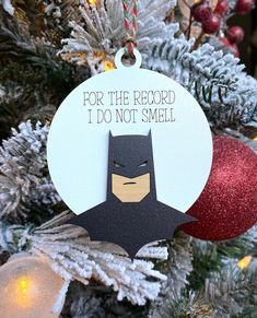 a batman ornament hanging on a christmas tree with ornaments around it that says for the record i do not smell