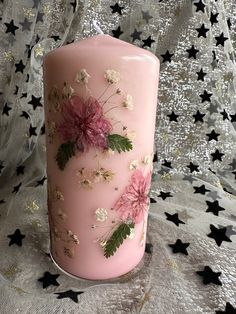 a pink candle decorated with flowers and leaves