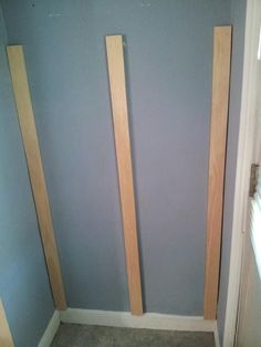 two wooden poles are in the corner of a room with blue walls and gray carpet