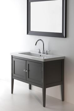 a bathroom sink sitting under a mirror next to a wall mounted faucet and a framed mirror