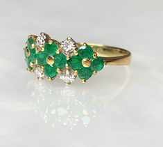 Emerald Flower Ring, Emerald Ring For Women, Emerald Ring Vintage, Natural Emerald Ring, Emerald Dainty Ring, Emerald Solid 18k Gold Ring A delightful vintage solid 18k gold floral ring featuring 12 lively green round emeralds weighing 0.75 carats forming 3 flowers side by side while accented by 4 sparkling white diamonds weighing 0.15 carats. *Ring size: US 7 1/2 * Complimentary resizing is available up to 3 sizes larger or smaller than stated size. Formal Multi-stone Yellow Gold Flower Ring, Yellow Gold Flower-shaped Multi-stone Rings, Elegant Multi-stone Flower Ring, Yellow Gold Flower-shaped Rings With Multi-stone, Yellow Gold Floral Multi-stone Rings, Yellow Gold Cluster Emerald Ring Fine Jewelry, Elegant Flower-shaped Multi-stone Rings, Diamond Multi-stone Flower Ring, Flower Shaped Diamond Ring With Multi-stones