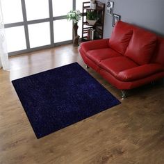 a living room with a red leather couch and blue rug on the wooden flooring