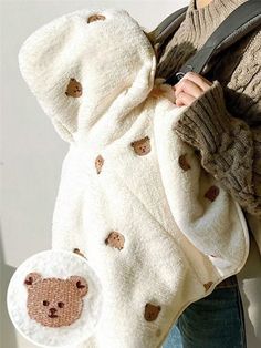 a woman is holding a teddy bear blanket over her shoulder while wearing a handbag