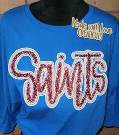 This listing is for a SAINTS unisex shirt. This embroidered shirt comes in colors/fabric prints of your choice.  THIS LISTING IS ONLY FOR THE MASCOT SHIRT PICTURED AND LISTED ABOVE  OTHER MASCOTS ARE AVAILABLE PLEASE MESSAGE US OR BROWSE OUR SHOP. IF THIS SHIRT IS ORDERED AND YOU PUT ANOTHER MASCOT NAME IT WILL BE CANCELLED. Feel free to request color changes. If you have no special requests, your design will resemble the first picture in the listing as closely as possible. Some fabrics in the applique design may differ slightly depending on availability of fabric. We use a mix of HTV glitter or glitter fabric and sequins on our designs.  We use unisex Gildan brand sweatshirts, Gildan softstyle t-shirt and Gildan long sleeve shirt for most orders we also use other brands when needed.  We d Glitter Football Shirts, Saints Shirts, Spirit Shirts, Glitter Fabric, Branded Sweatshirts, Team Shirts, Clothes Crafts, School Spirit, School Shirts