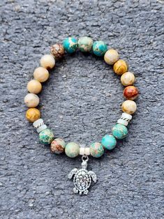 Dive into the beauty of the ocean with "Turtle Beach", featuring a charming Turtle charm and a stunning combination of gemstones. The Green Sea Sediment Jasper is believed to enhance communication and intuition, while the Fossilized Coral is said to bring inner peace and tranquility. The Mother of Pearl spacers add a touch of elegance and sophistication to the design. The Turtle charm is a symbol of wisdom, patience, and longevity, reminding you to embrace the journey of life and to trust in the 8mm Bead Bracelet For Beach, Agate Bead Jewelry For Beach, Spiritual 8mm Beads Jewelry For Beach, Gemstone Beads Bracelet Jewelry For Beach, Beach Jewelry With Natural Agate Stones, Agate Jewelry With Natural Stones For Beach, Beach Charm Bracelet, Tropical Jewelry, Fossilized Coral