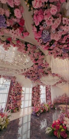 a room filled with lots of flowers and chandelier hanging from the ceiling above it