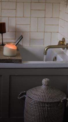 a bathroom sink with a basket next to it and a candle on the counter top