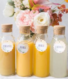 three bottles filled with liquid sitting on top of a table next to flowers and a vase