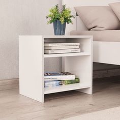 a white book shelf with books and a plant on the top, in front of a bed