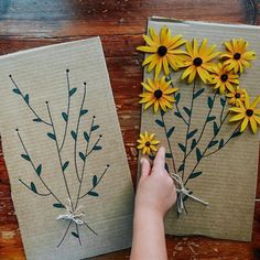 two handmade notebooks with yellow flowers on them, one being held by a woman's hand