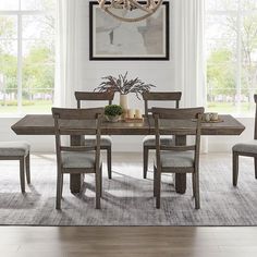 a dinning room table with chairs and a chandelier above it in front of windows