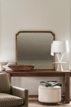 a living room with a chair, ottoman and mirror