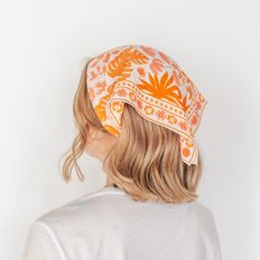 a woman with blonde hair wearing an orange and white patterned bandana on her head