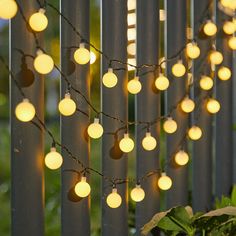 some lights are hanging on the side of a fence