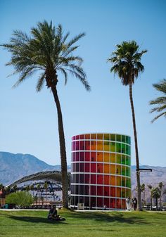 a colorful building with palm trees in the foreground and mountains in the back ground