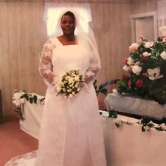 a woman in a wedding dress standing next to flowers