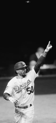 a black and white photo of a baseball player holding his arm up in the air