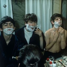 three men shaving their faces in front of a mirror while others look at them