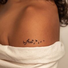 the back of a woman's shoulder with birds and words on her left arm