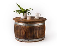 a potted plant sitting on top of a wooden barrel next to two mugs