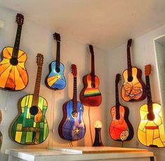 several guitars are hanging on the wall in a room with stained glass windows and lights