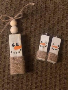 two snowmen made out of toilet paper and twine on top of a brown carpet