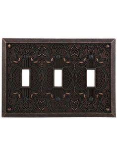 an ornate cast iron outlet cover with two toggles and decorative designs on the front