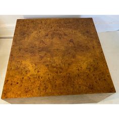 a square wooden table sitting on top of a white floor