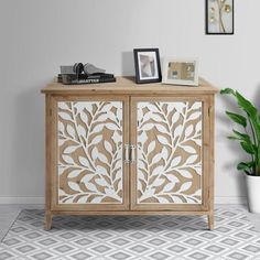 a white and brown cabinet sitting on top of a floor next to a potted plant