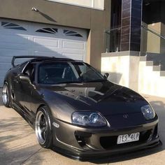 a silver sports car parked in front of a garage