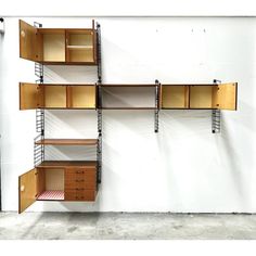 a wall mounted shelving unit with drawers and shelves on each shelf, in front of a white wall