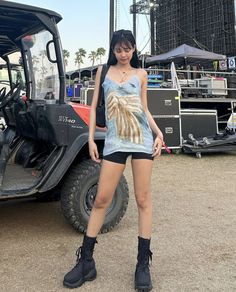 a woman standing in front of a golf cart with her legs crossed and black boots on