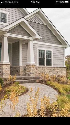 a gray house with white trim and stone steps leading to the front door is shown